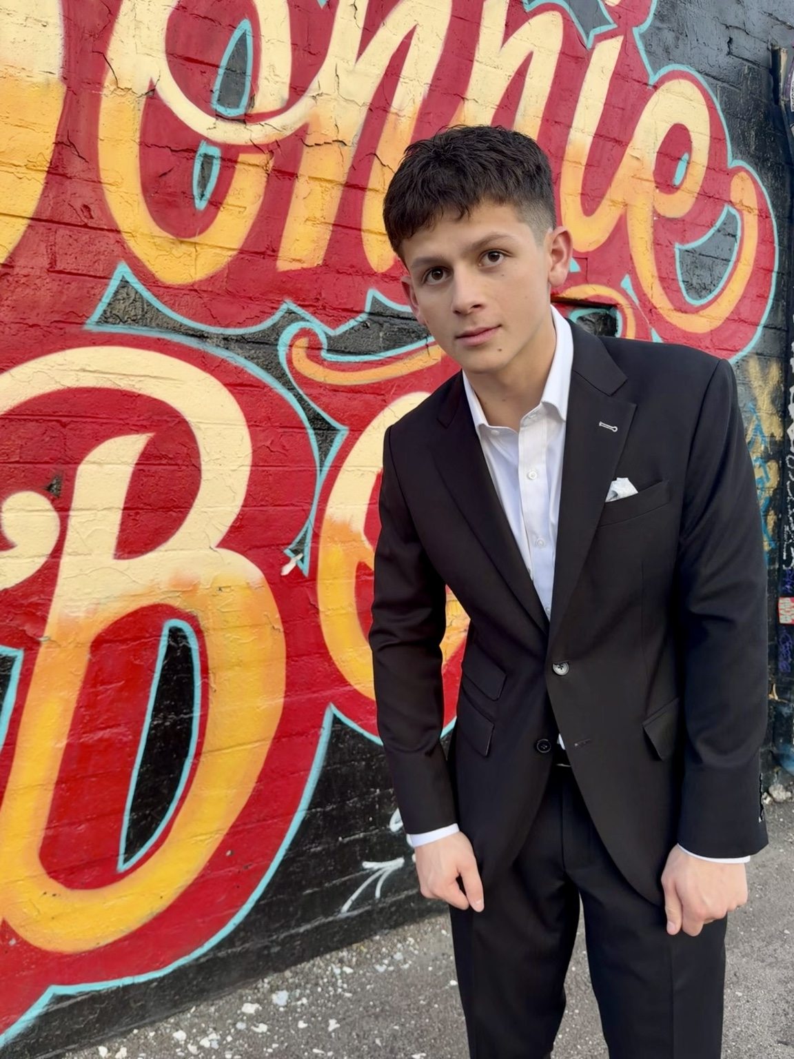 Donnie in a black suit against colorful graffiti